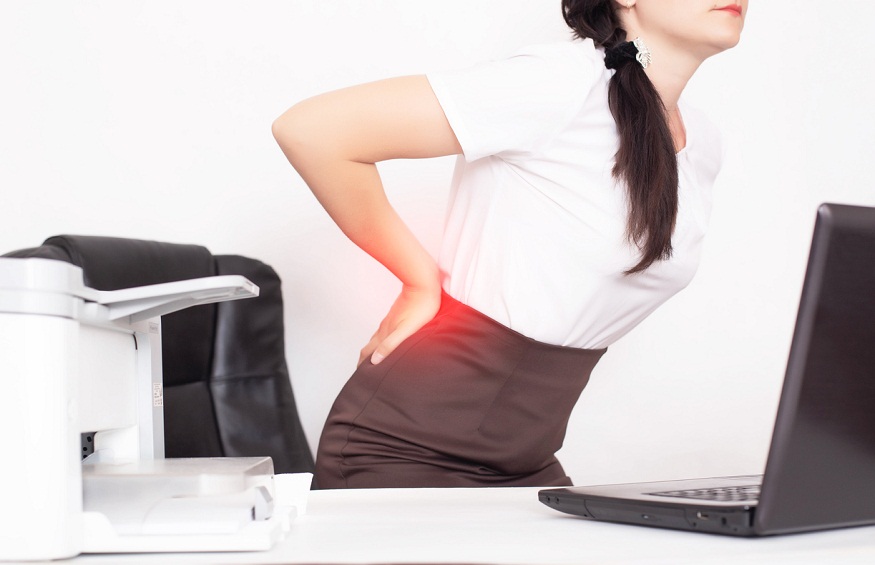 girl office worker holding her aching back from a chair, the concept of back pain in office workers, lactic acid in muscles and spinal problems, lumbago